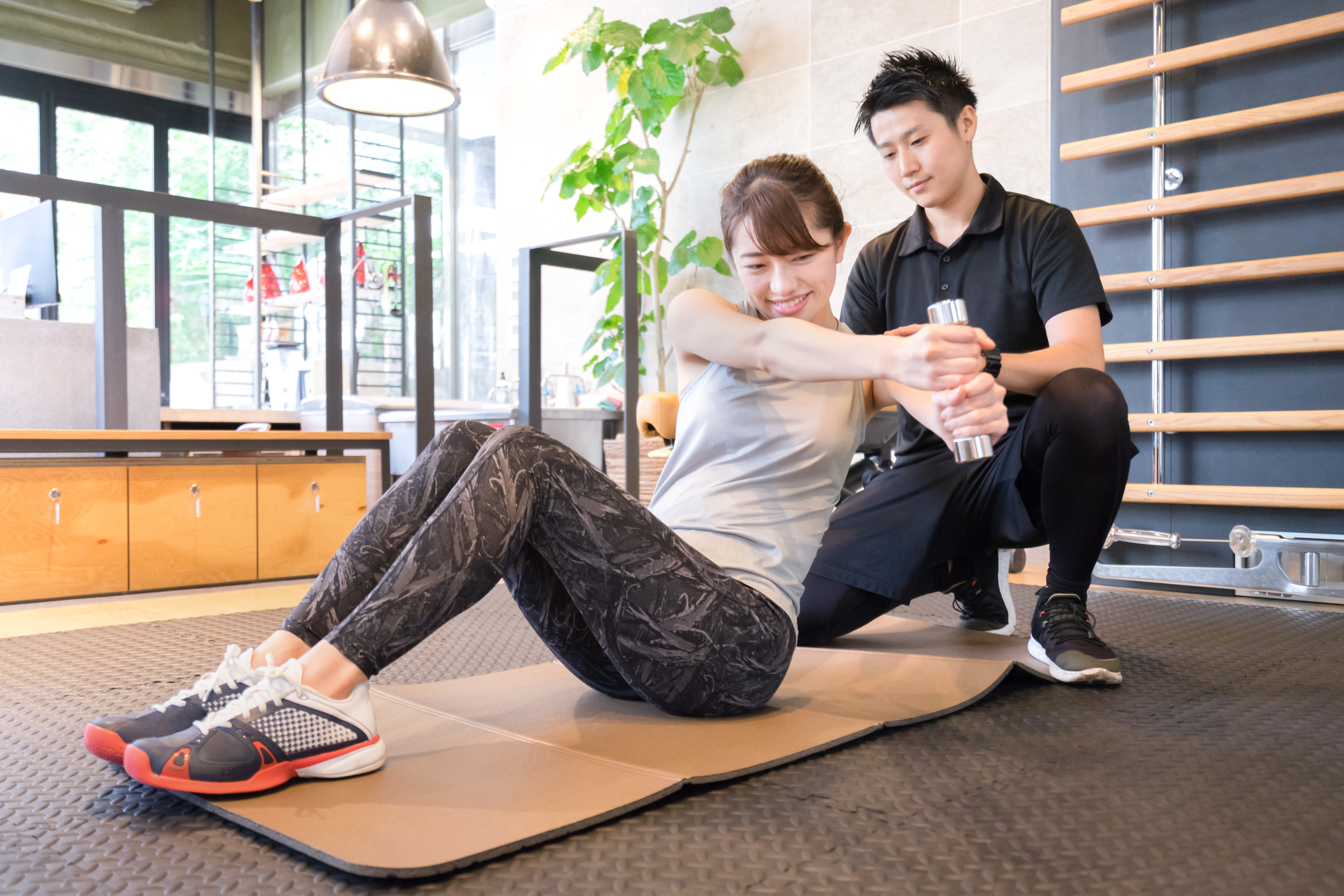 男性トレーナーの指導のもとトレーニングを受けている女性